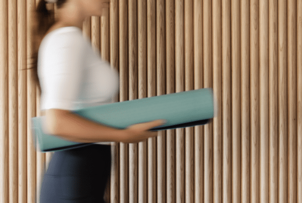 Blurred person in a white top carries a teal folder while walking past vertical wooden slats.