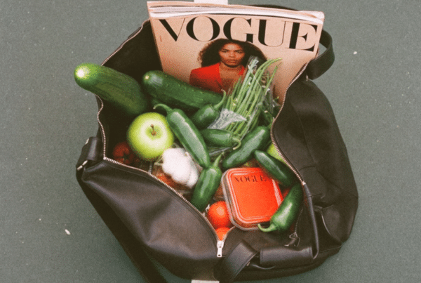 Open black bag filled with groceries, with a Vogue magazine peeking out from the top.